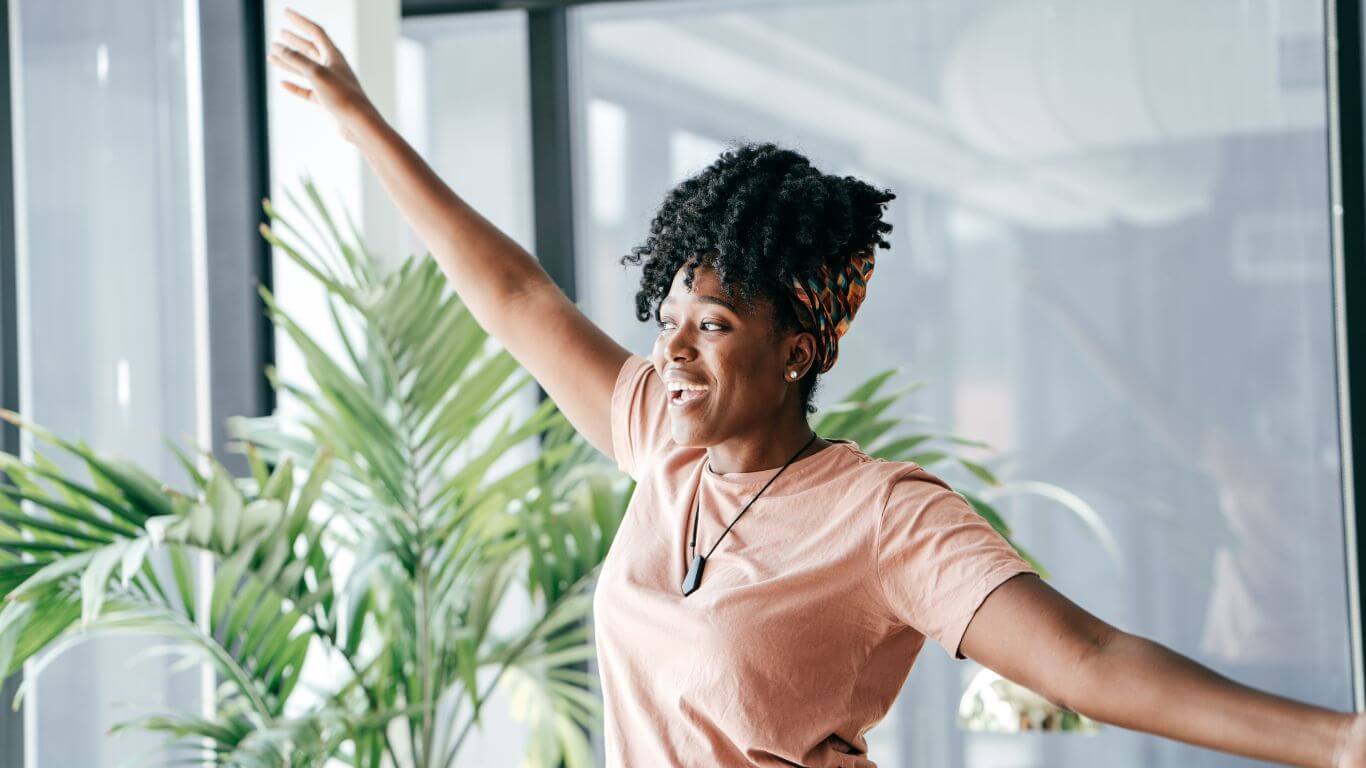 Photo of a woman looking joyful in an work environment. She looks like she has a high level of well-being.